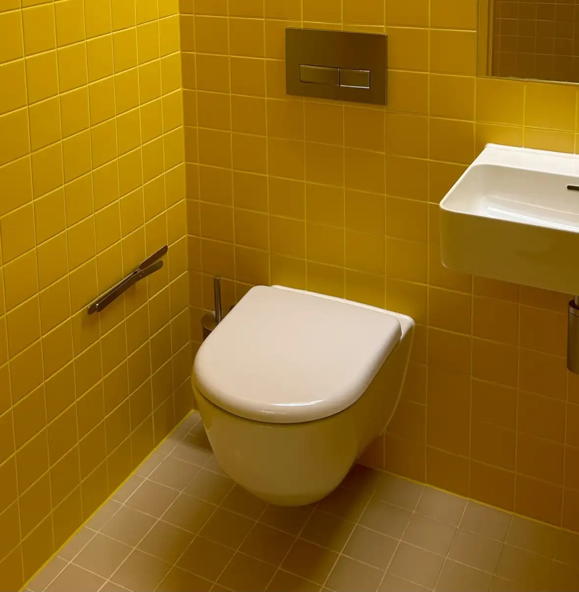 Ny fugning omkring væghængt toilet i badeværelse med gule fliser