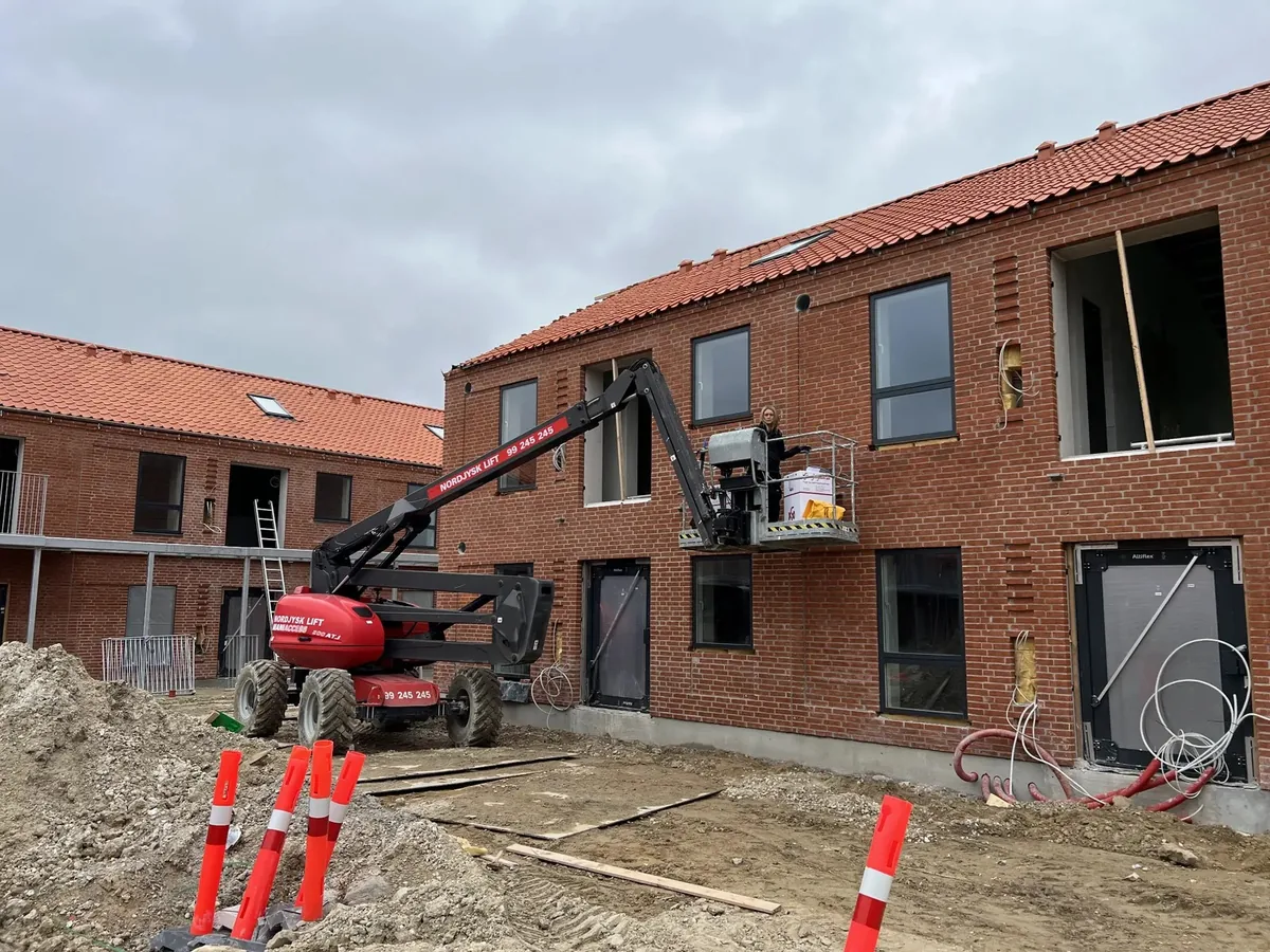 Fugearbejde i gang på nybyggeri i mursten, hvor dilatationsfuger udføres fra lift ved etageejendom.