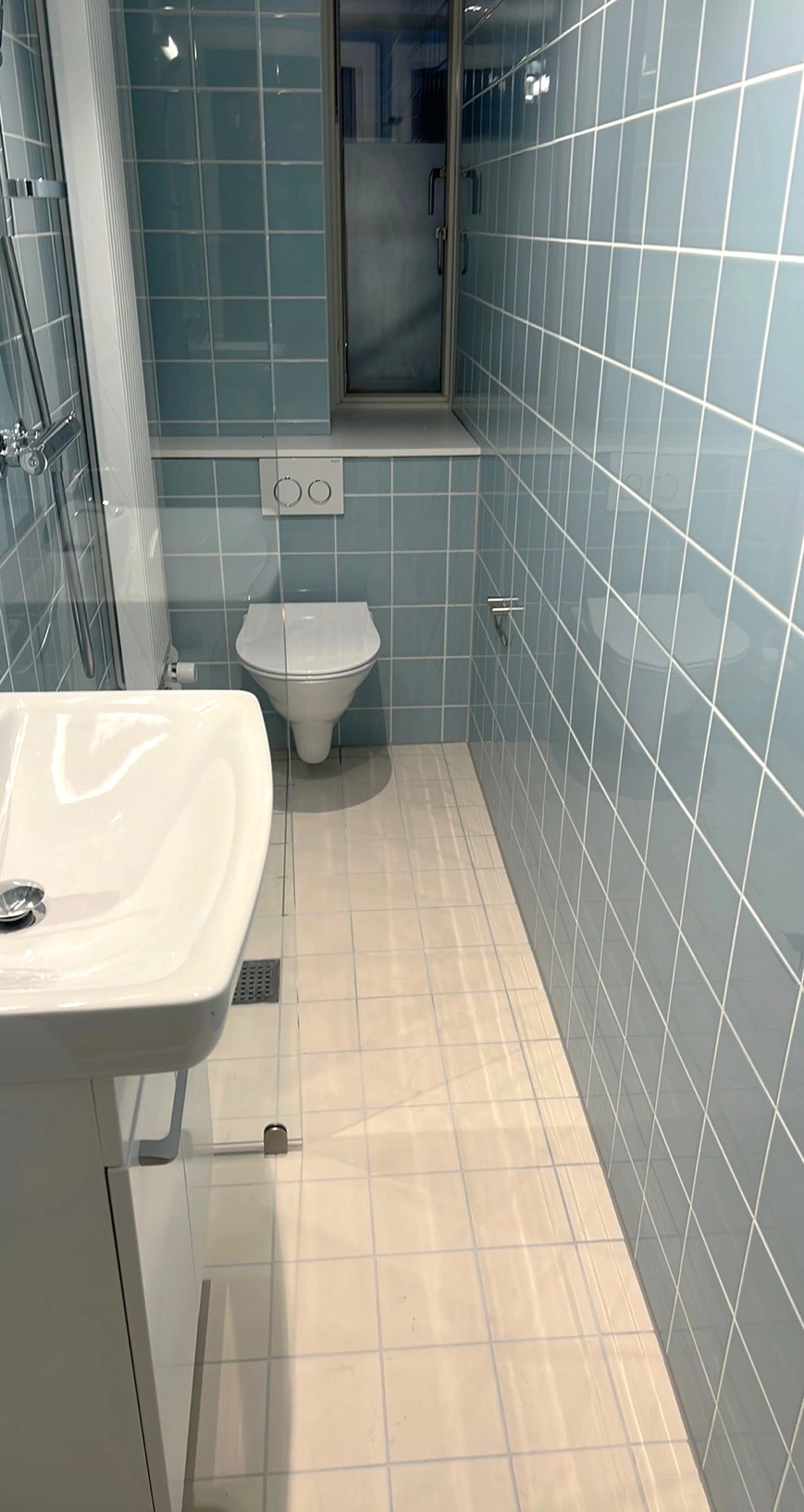 Færdigt renoveret badeværelse på Fynshuse i København NV med toilet, håndvask og fugede flisesamlinger