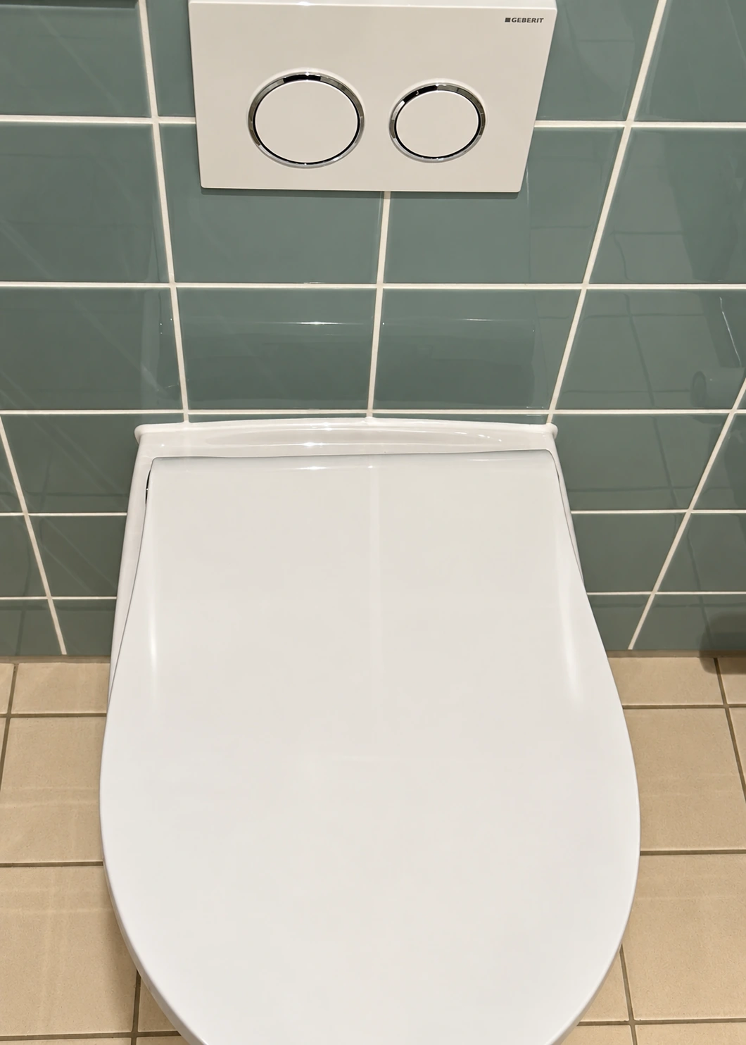 Hvid sanitetsfuge mellem væghængt toilet og blå flisevæg på Fynshuse i København NV