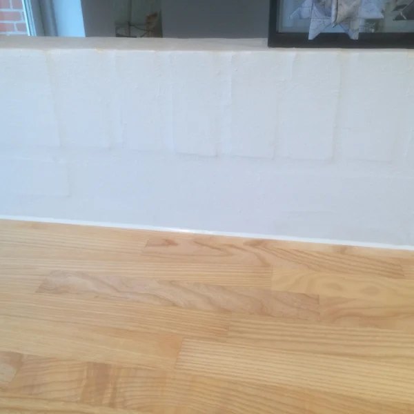 Detalje af hvid fuge mellem lys træbordplade og væg i køkken i Holbæk