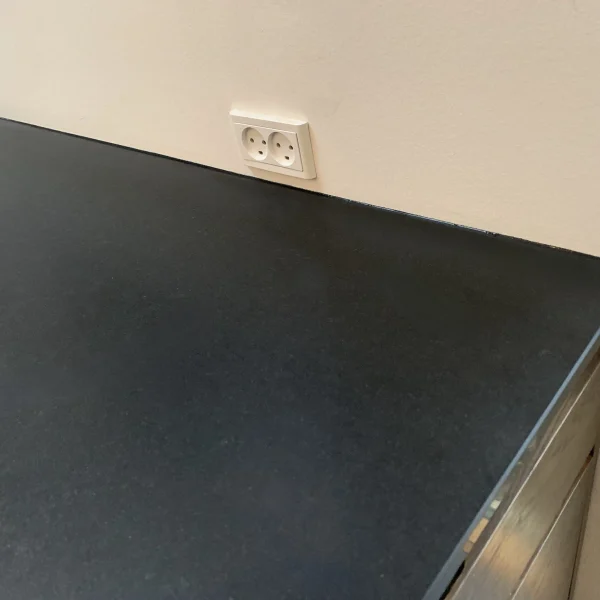 Fugning af sort stenbordplade langs væg i køkken